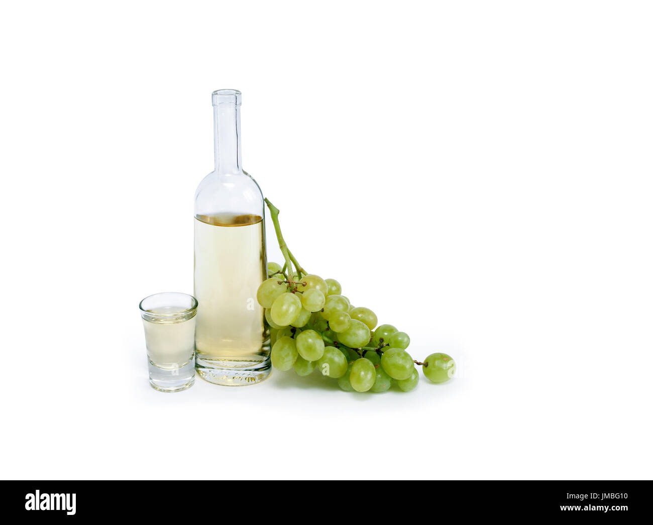 Open bottle of grappa near wineglass and bunch of grapes on white background. Clipping path is included Stock Photo