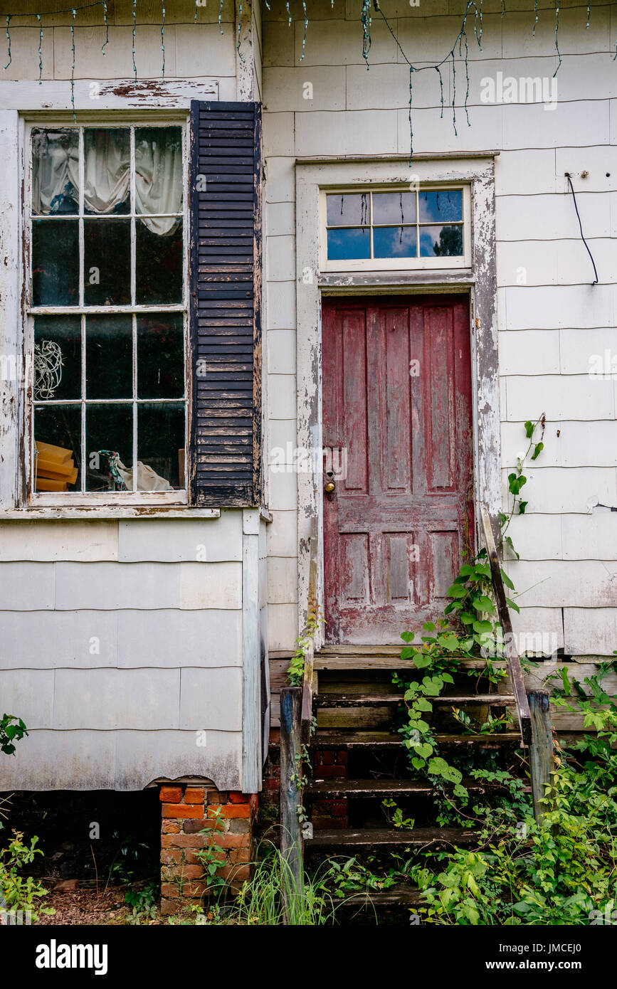 Entrance to an abandoned building that once had a bright red door showing the look of poverty in the USA. Stock Photo