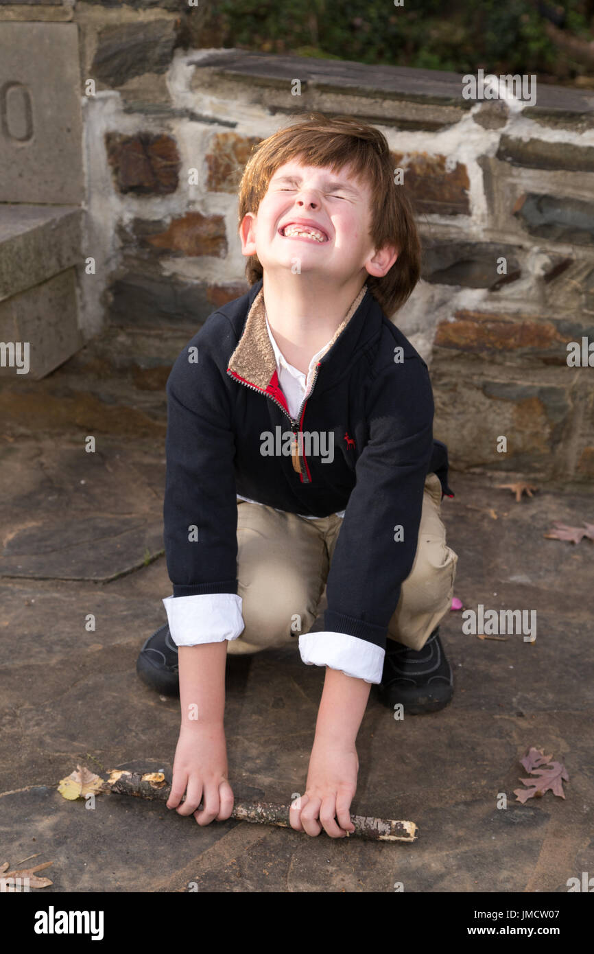 Young boy pretending stick is heavy Stock Photo