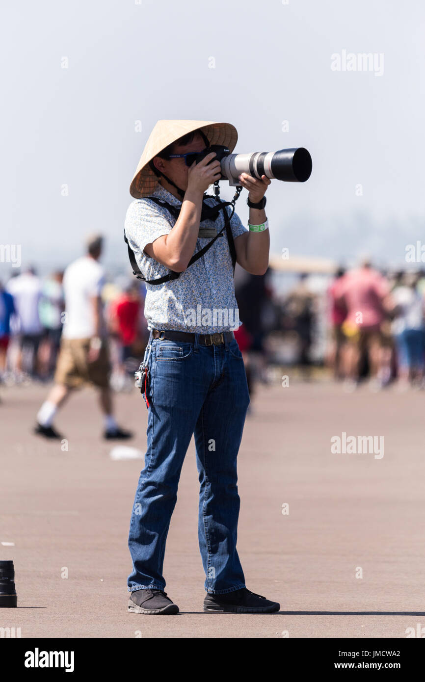 Guy wearing conical straw hat taking photos Stock Photo