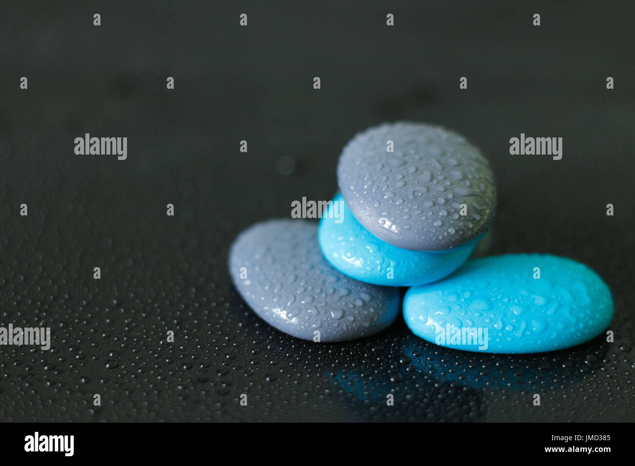 Blue and gray pebbles with drops of water arranged in zen lifestyle on black background Stock Photo