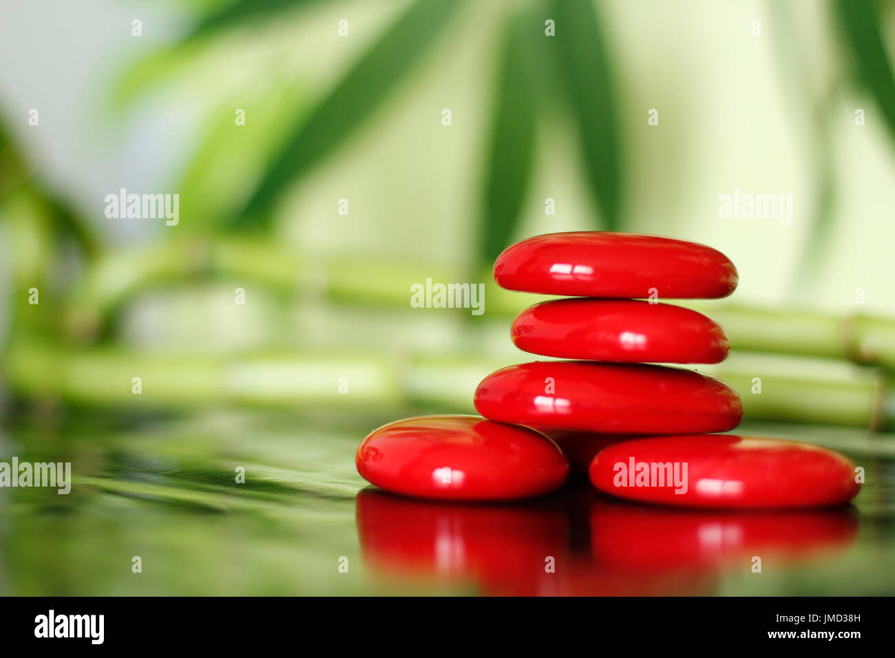 Red stones arranged in lifestyle zen on shiny floor and back plan of leaf and bamboo Stock Photo
