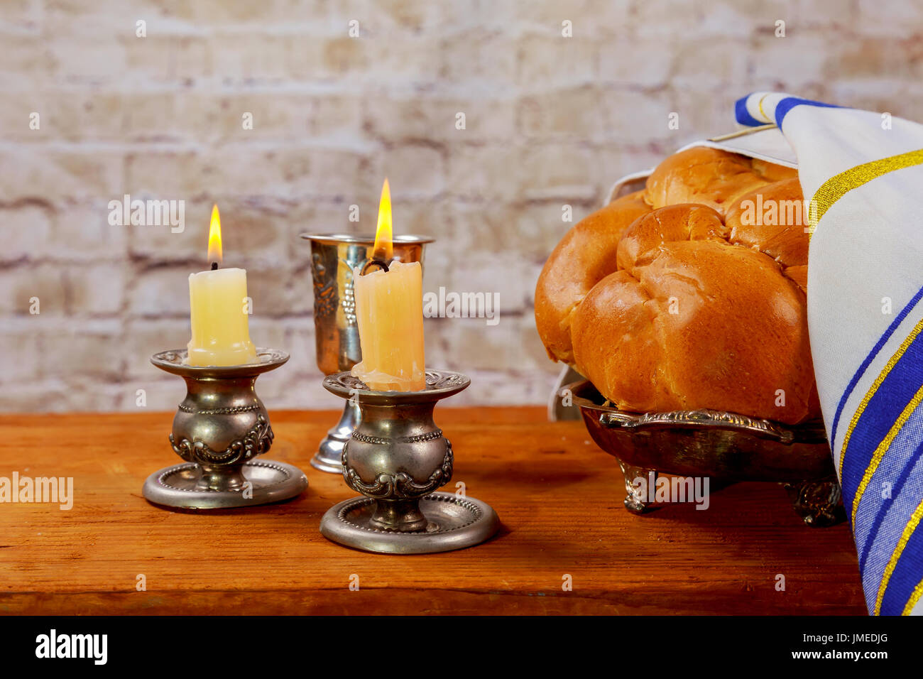 Shabbat candles in glass candlesticks with blurred covered challah