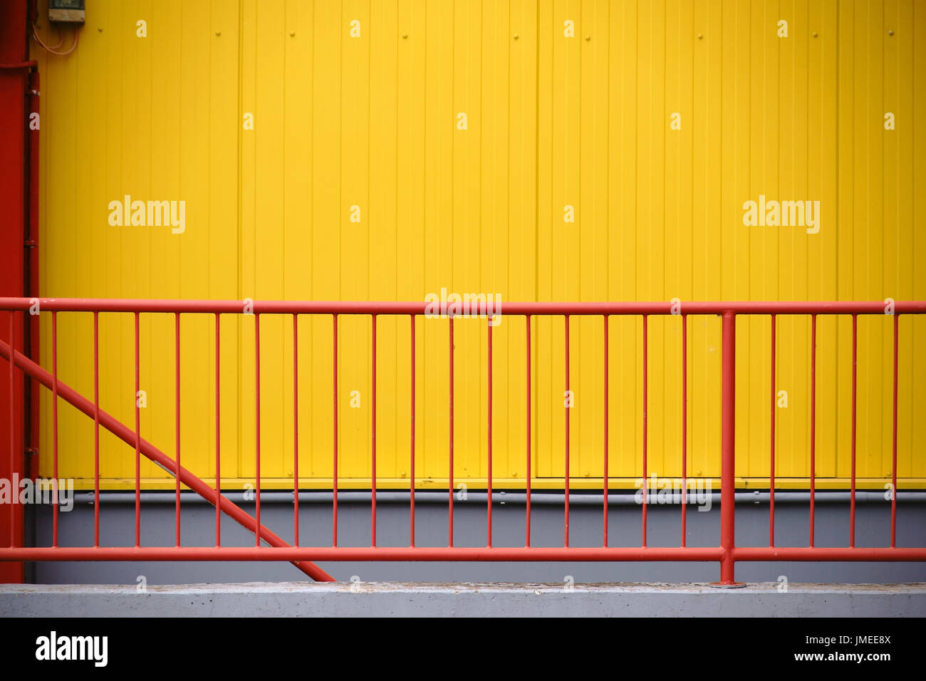 Red Factor Railing A colorful red railing in front of the yellow checkered facade of a ...