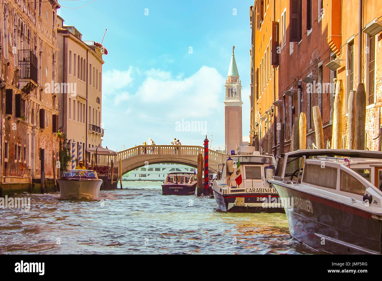 Muted colors and soft focus image of a beautiful day in Venice with the Bell Tower and bridge with couple on it and police boats in the lagoon Stock Photo