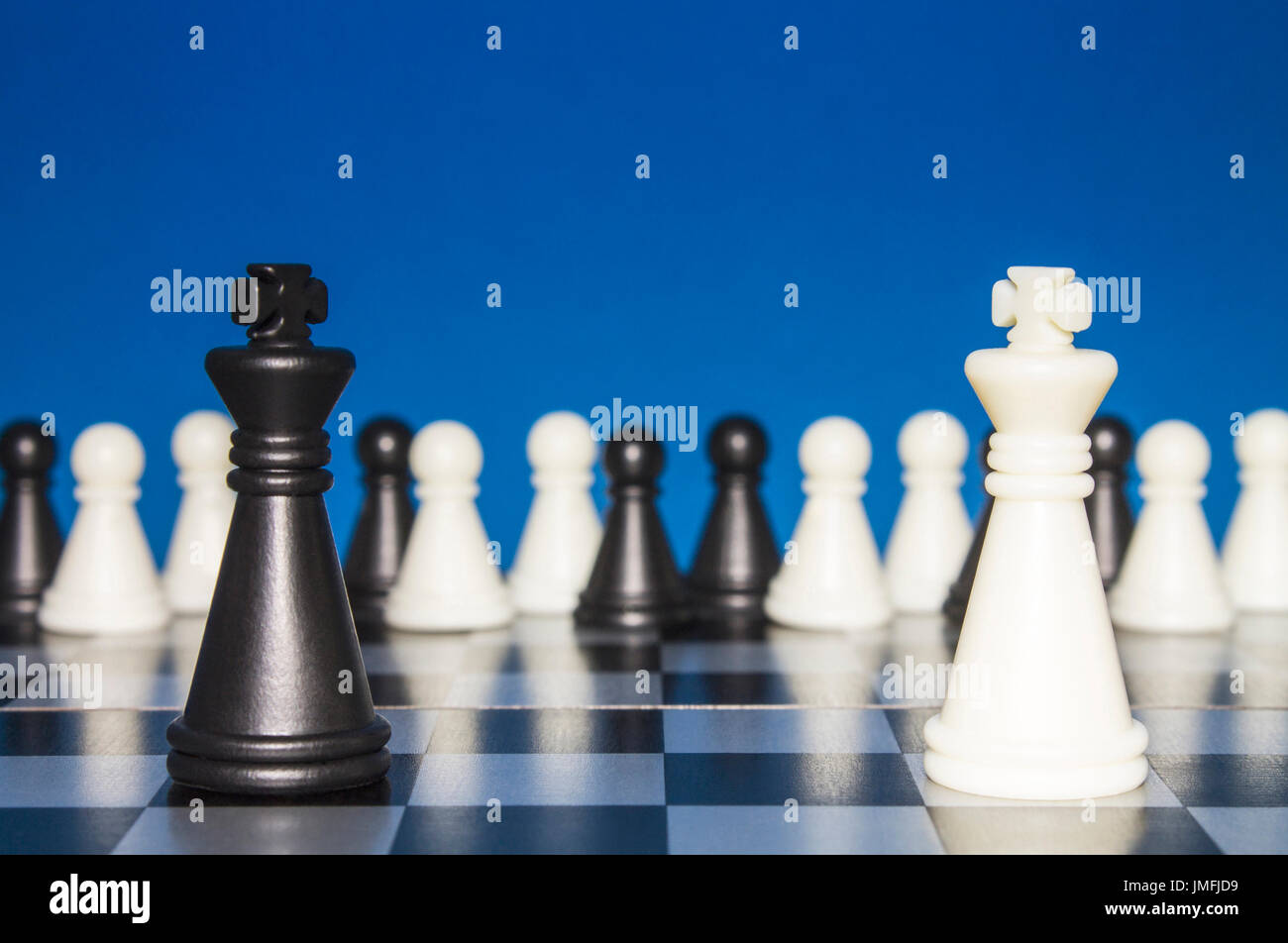 Chess as a policy. A lonely black figure against a lone white figure. A large group of the public looks from the outside. Stock Photo