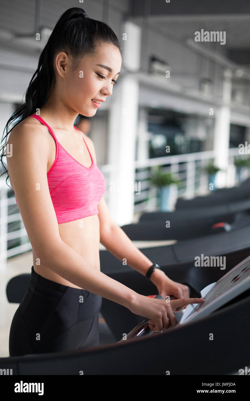 Young Chinese woman exercising on treadmill in gym Stock Photo