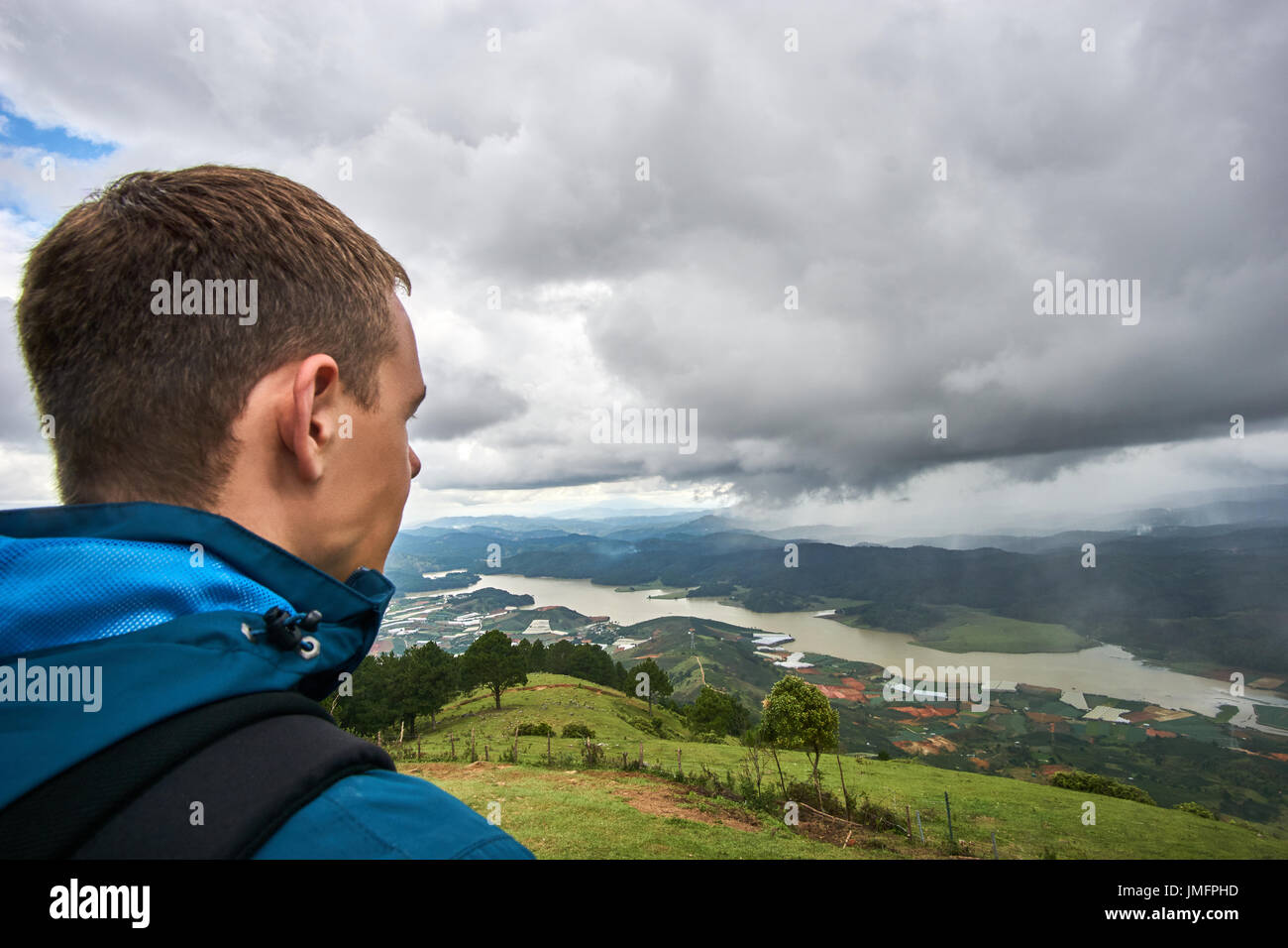 Young man standing on the mountain lang biang in Da-lat, Vietnam. Dramatic sky before the rain starts. Stock Photo