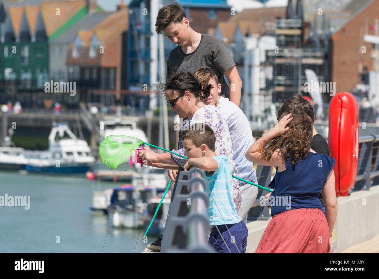 Crab fishing. Young people fishing for crabs by the river in Littlehampton, West Sussex, England, UK. Stock Photo