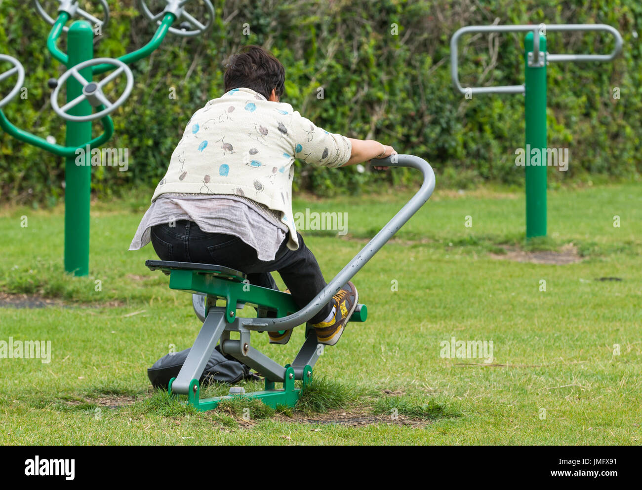 Outdoor gym. Middle aged lady using apparatus at an outside gym in Worthing, West Sussex, England, UK. Stock Photo
