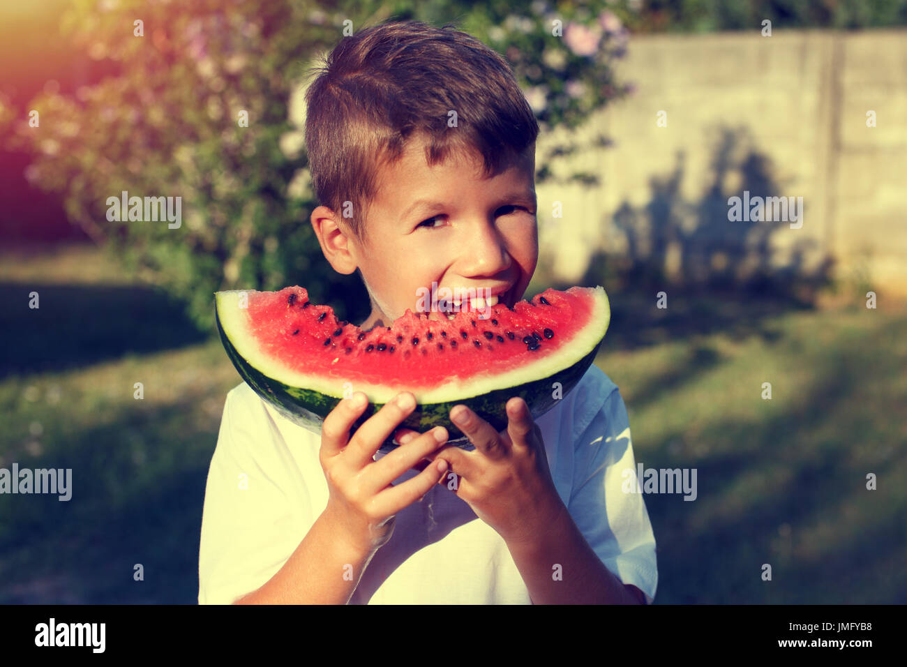 Little boy with smile bite into slice of watermelon outdoor Stock Photo