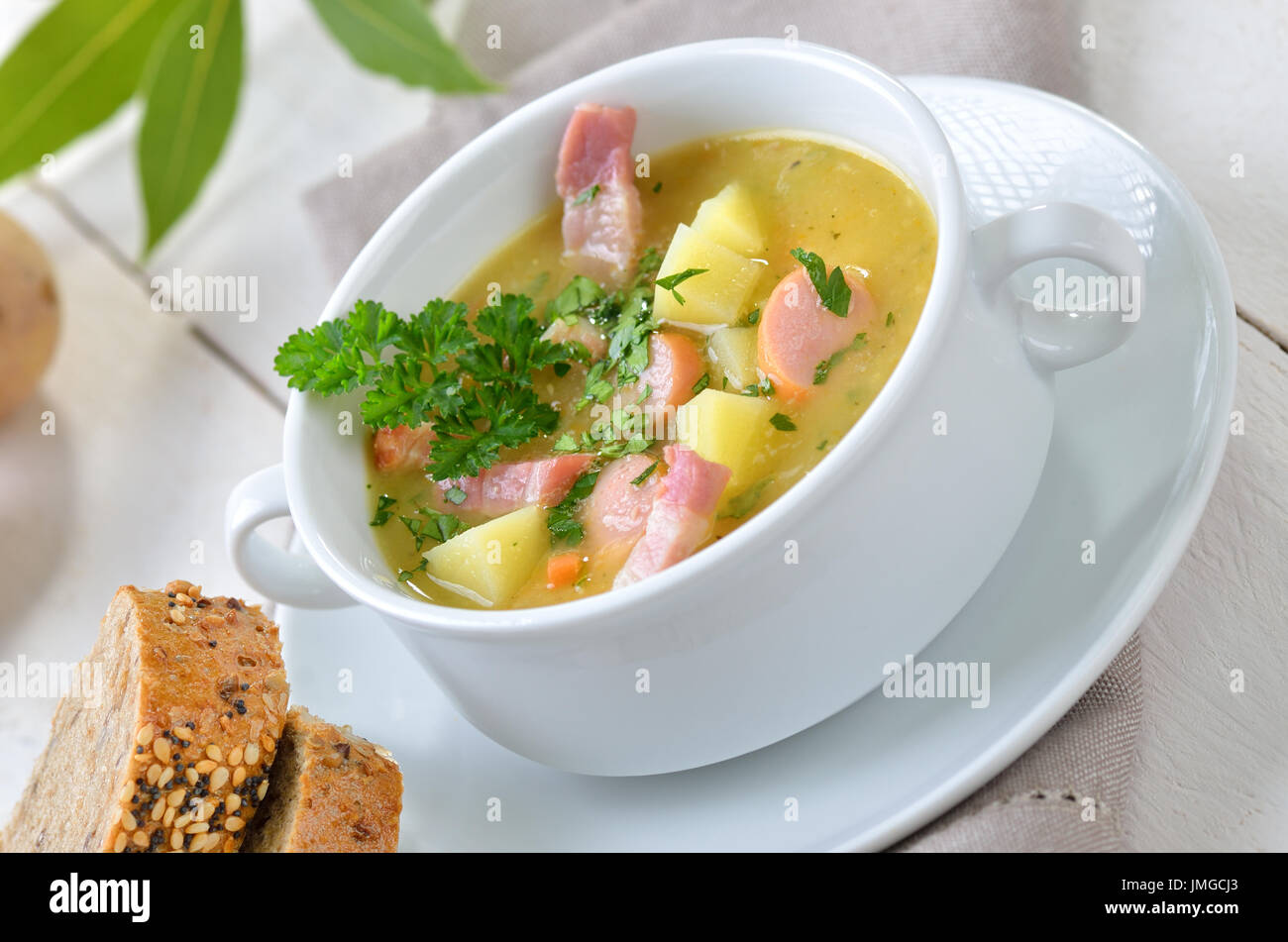 Freshly made potato soup with bacon strips and sausage wheels, served with bread Stock Photo