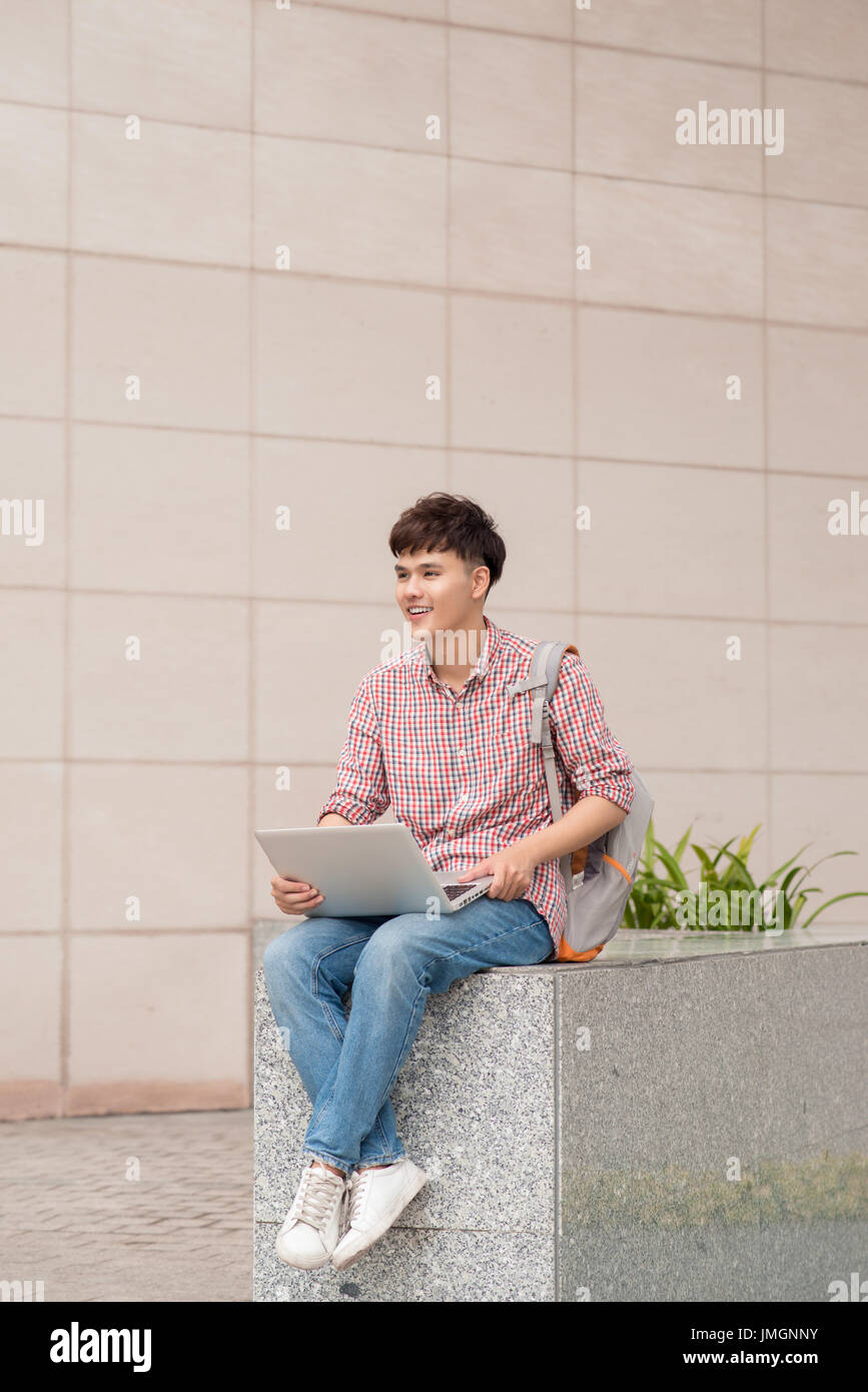 Male student using laptop in college campus Stock Photo