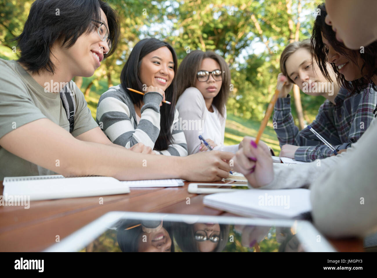 Image of multiethnic group of happy young students sitting and studying ...