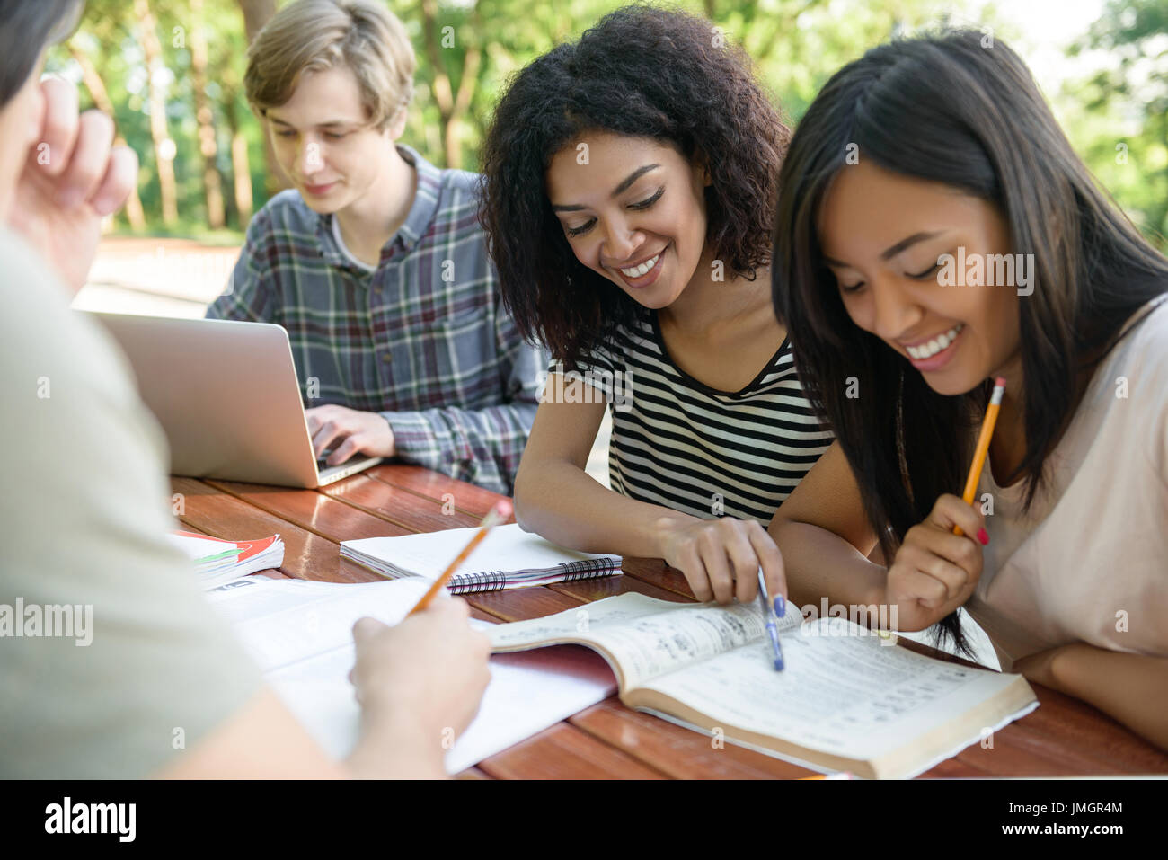 Image of multiethnic group of young happy students sitting and studying ...