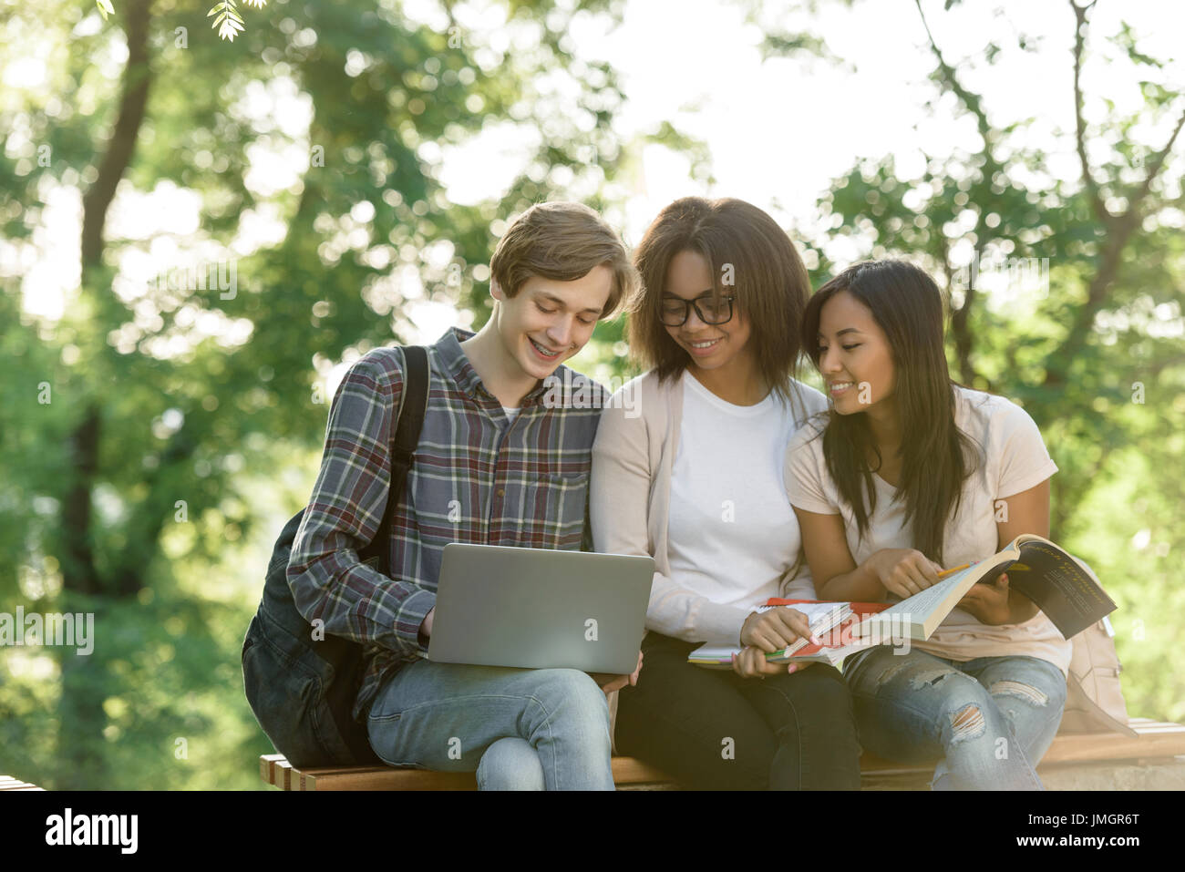 Image of multiethnic group of young happy students sitting and studying ...