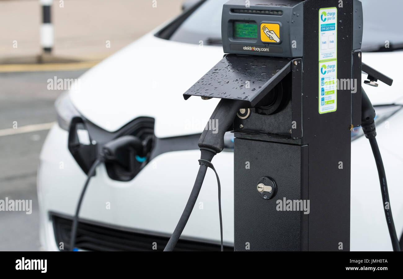 EV charging point with a small electric car plugged in while charging its batteries in Brighton, East Sussex, England, UK.. Green energy concept. Stock Photo