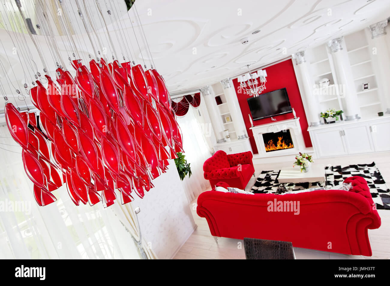 Classical living room interior in white and red colors with fireplace and beautiful lamp Stock Photo