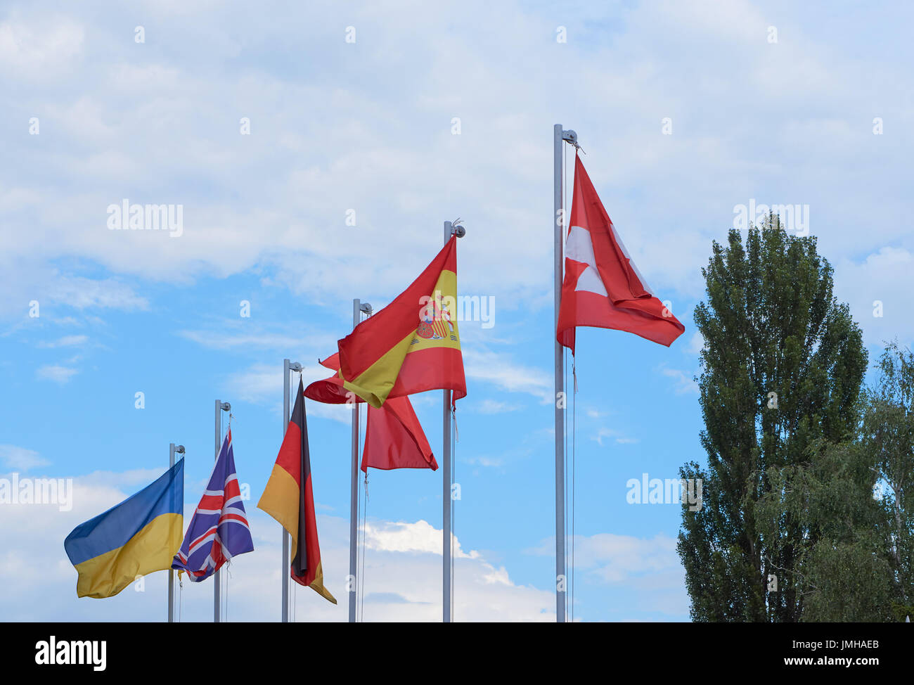 a group of european country flags waving on flag poles against blue sky ...