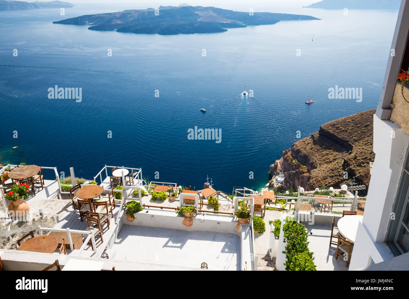 Fira, Thira town, Santorini, Cyclades islands, Greece. Beautiful view of the town with white buildings, blue church's roofs and many colored flowers. Stock Photo