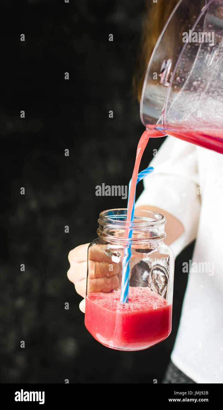 Female pouring watermelon smoothie in a glass jar Stock Photo