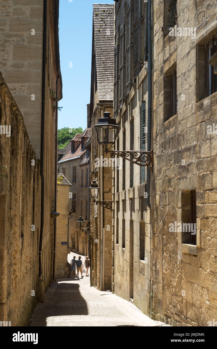 Three people walk down a narrow street in Sarlat-la-Canéda, Dordogne, France Stock Photo