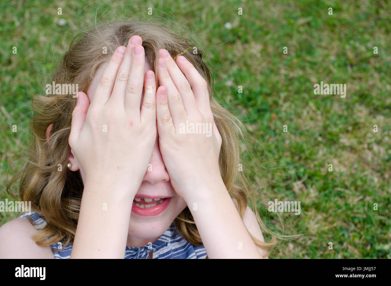 Little girl hiding face behind hands Stock Photo