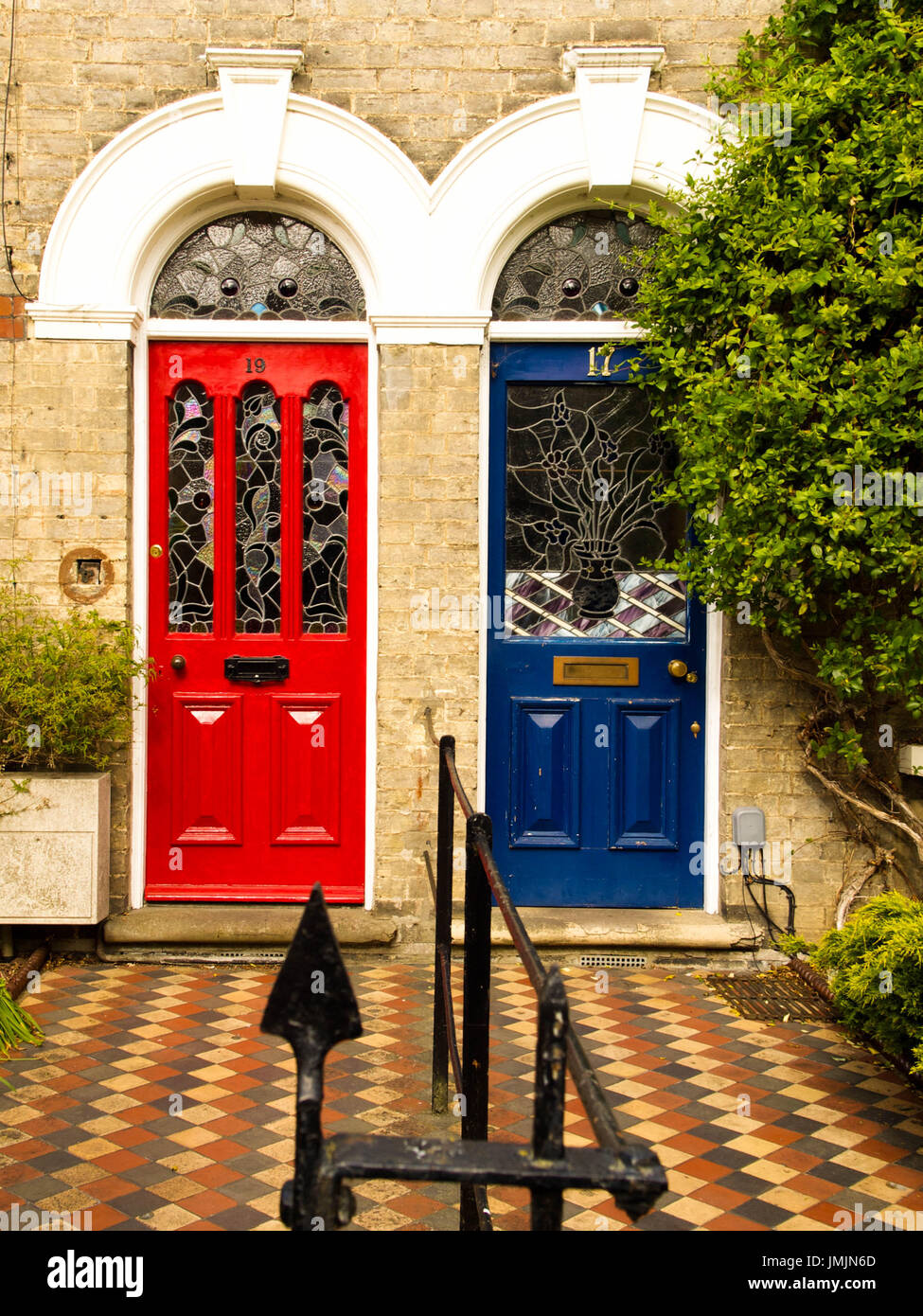 Red and Blue Terrace House Doors with Tiled Pavement and Stained Glass Stock Photo