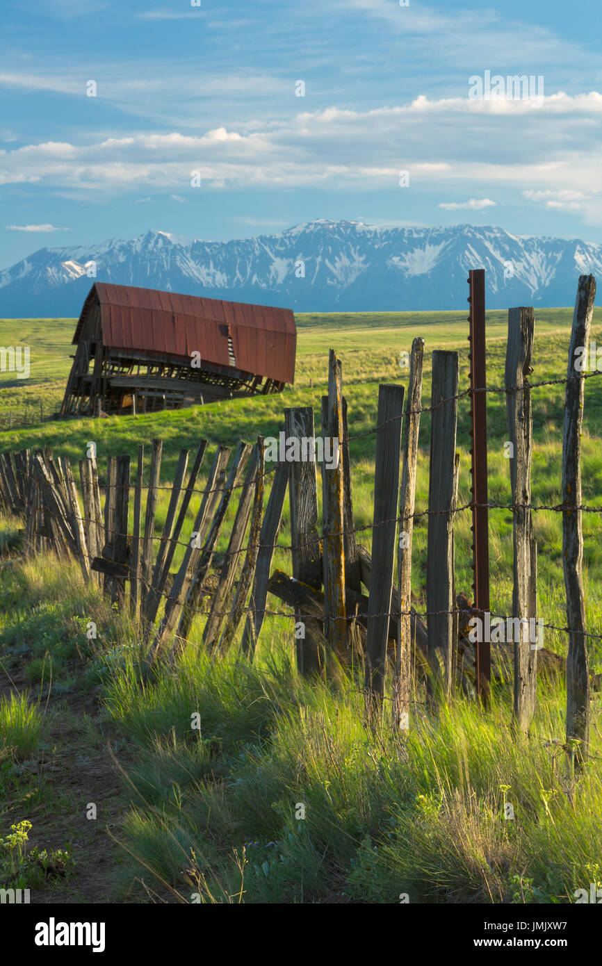 An old fence and barn in the Zumwalt Prairie of northeast Oregon and the Wallowa Mountains in the background. Oregon. USA. Spring Stock Photo