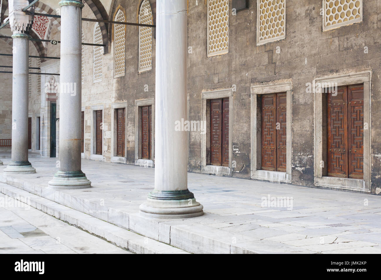 Portico with marble columns and doors in a row in the courtyard of an ancient mosque Stock Photo