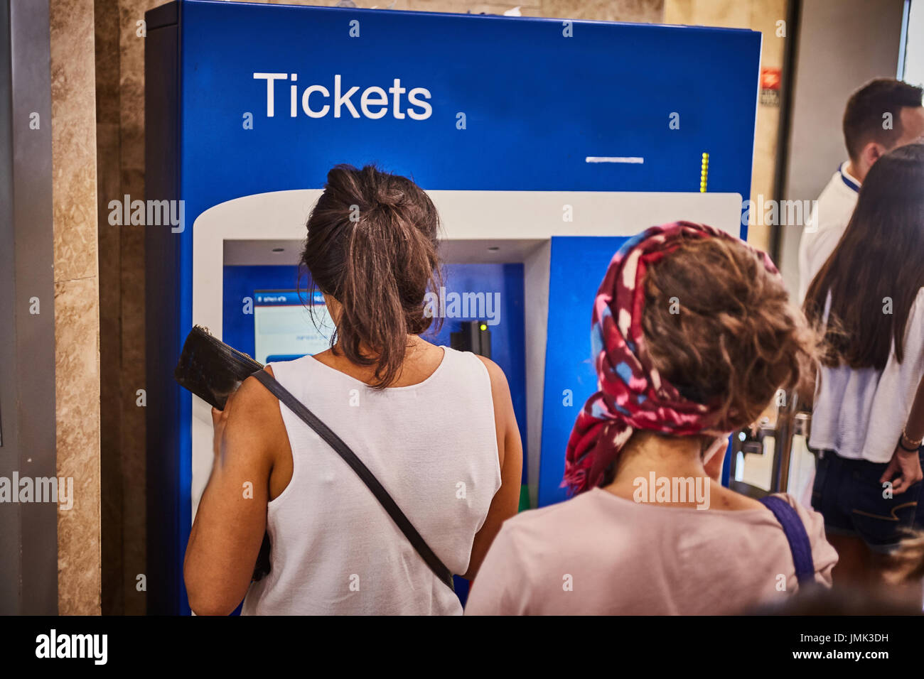 Woman bying tickets in a automated machine photo from behind Stock Photo