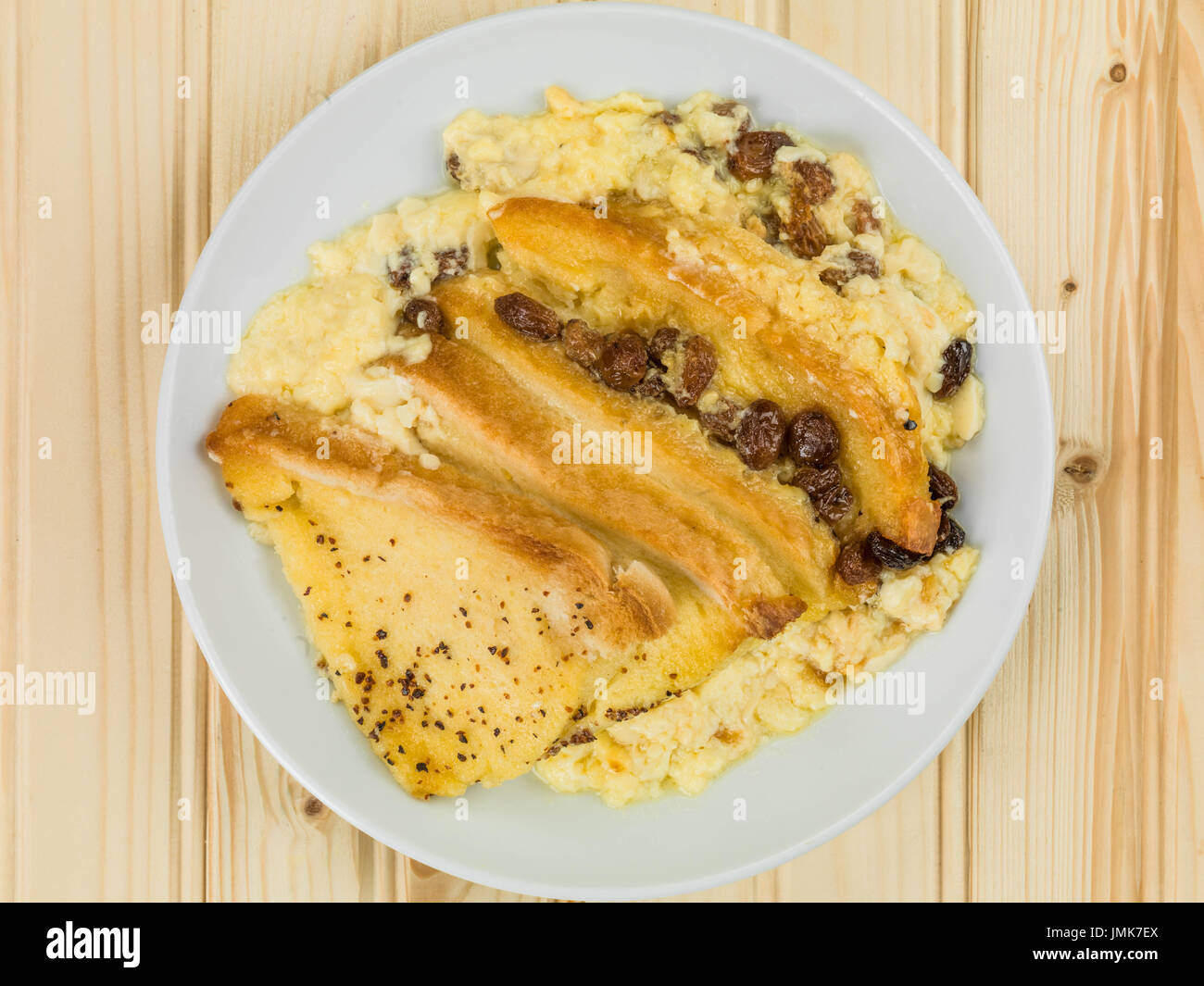 Traditional Bread and Butter Pudding Baked Dessert Against a Light Pine Wood Background Stock Photo