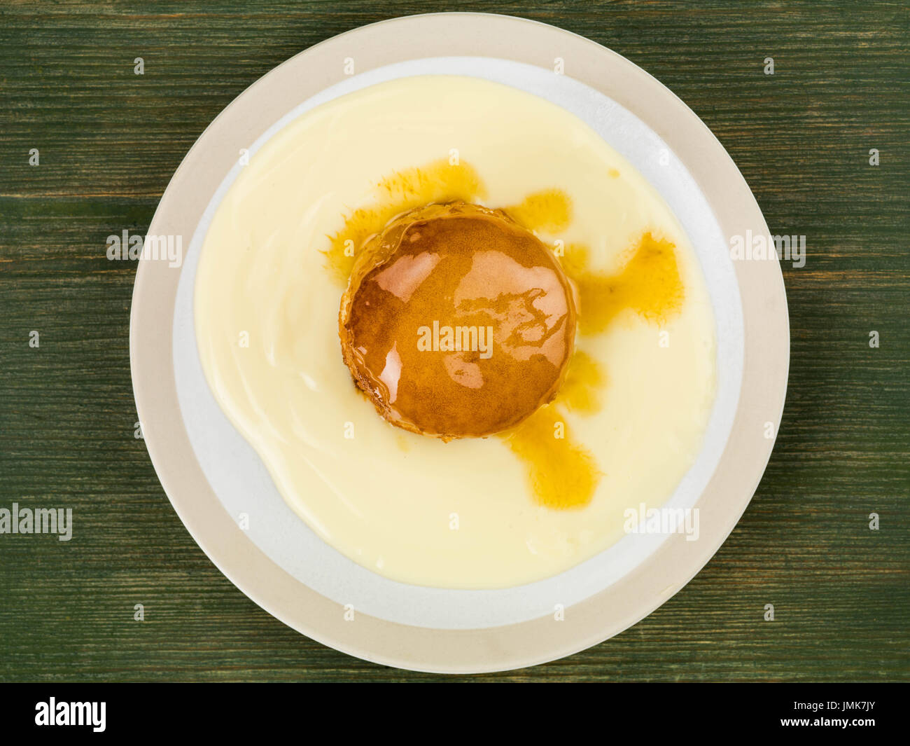 Syrup or Treacle Sponge Pudding With Custard Against a Green Wooden Background Stock Photo
