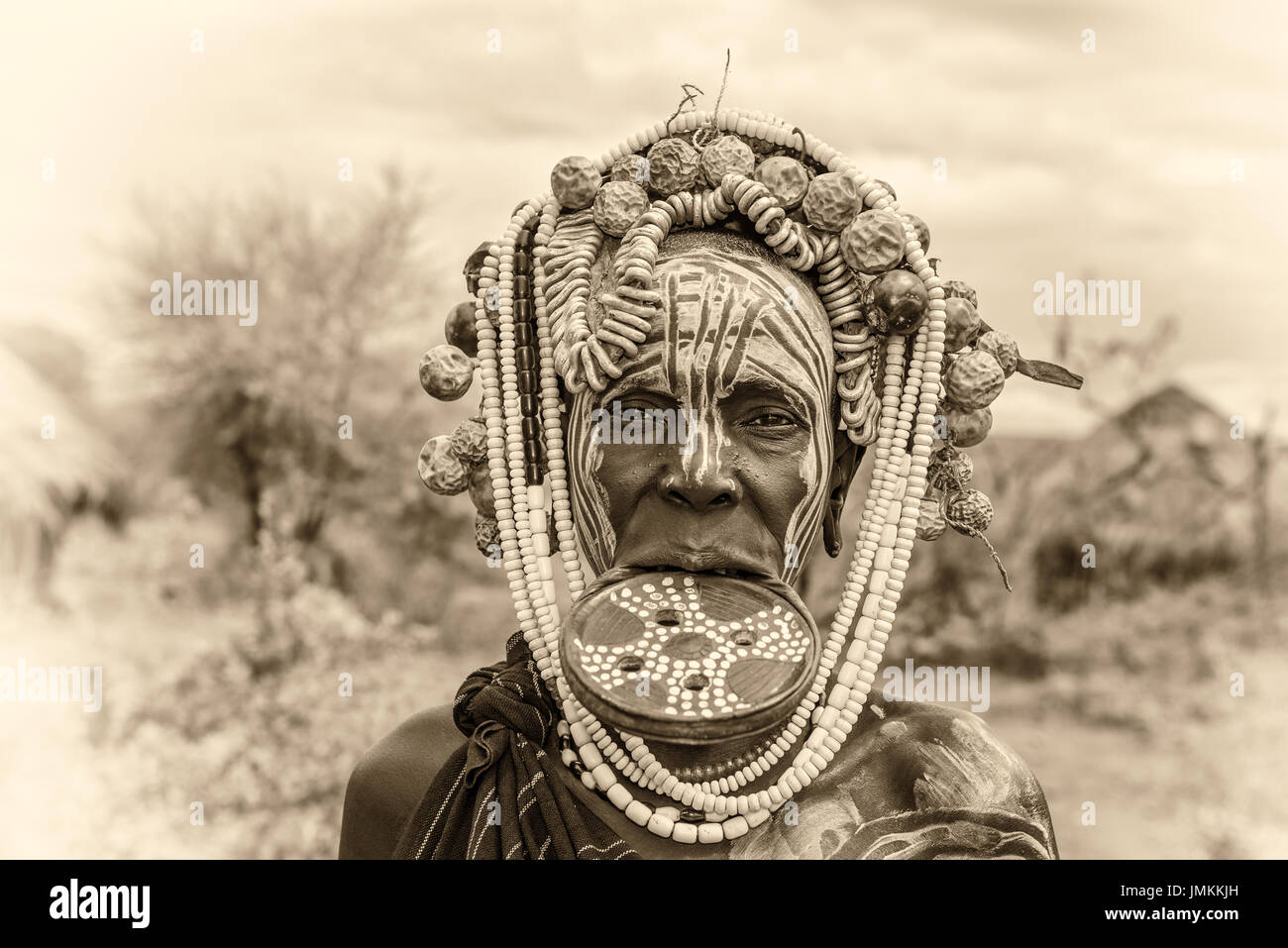 Woman from the african tribe Mursi with big lip plate in her village. Vintage black and white processed. Stock Photo