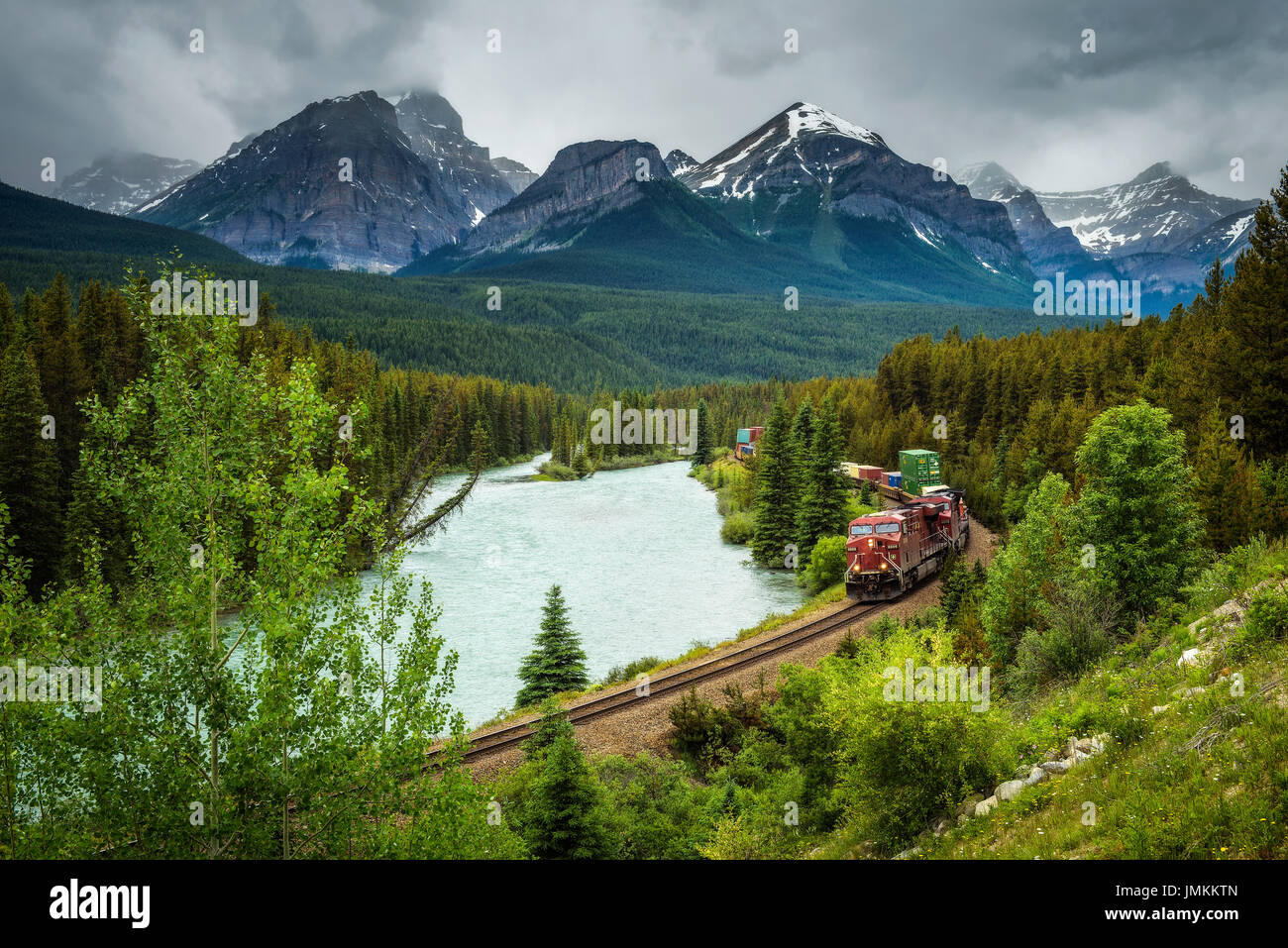 Train passing through the Morant's Curve in bow valley with Rocky Mountains in the background, Banff National Park, Alberta Canada Stock Photo