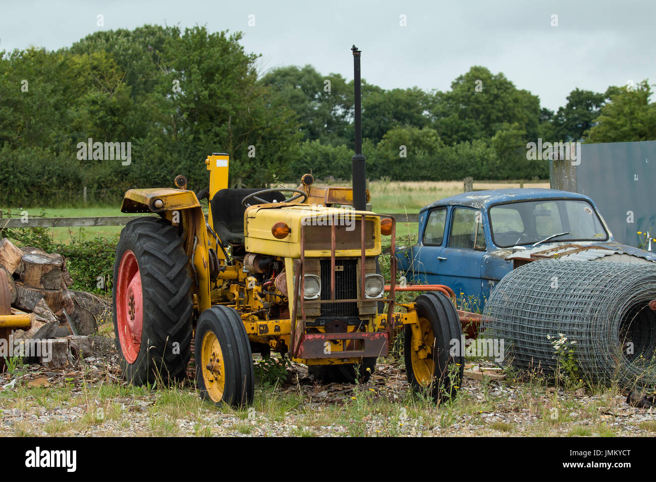 Old, rusting, yellow tractor on waste ground. Stock Photo
