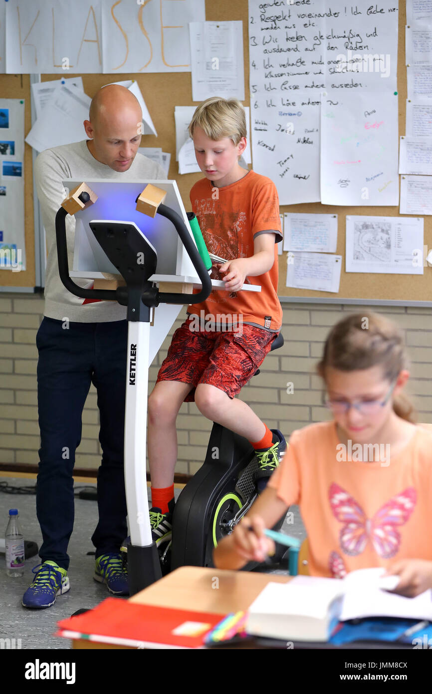 Aschaffenburg, Germany. 19th July, 2017. Class teacher Stefan Megerle talks to a year five pupil who is attending a German class while sitting on a bicycle at the Friedrich-Dessauer-Gymnasium (lit. Friedrich Dessau High School) in Aschaffenburg, Germany, 19 July 2017. The classroom has been equipped with five bicycles for a year. Pupils take turns riding the bicycles for at least one teaching period a day. Photo: Daniel Karmann/dpa/Alamy Live News Stock Photo