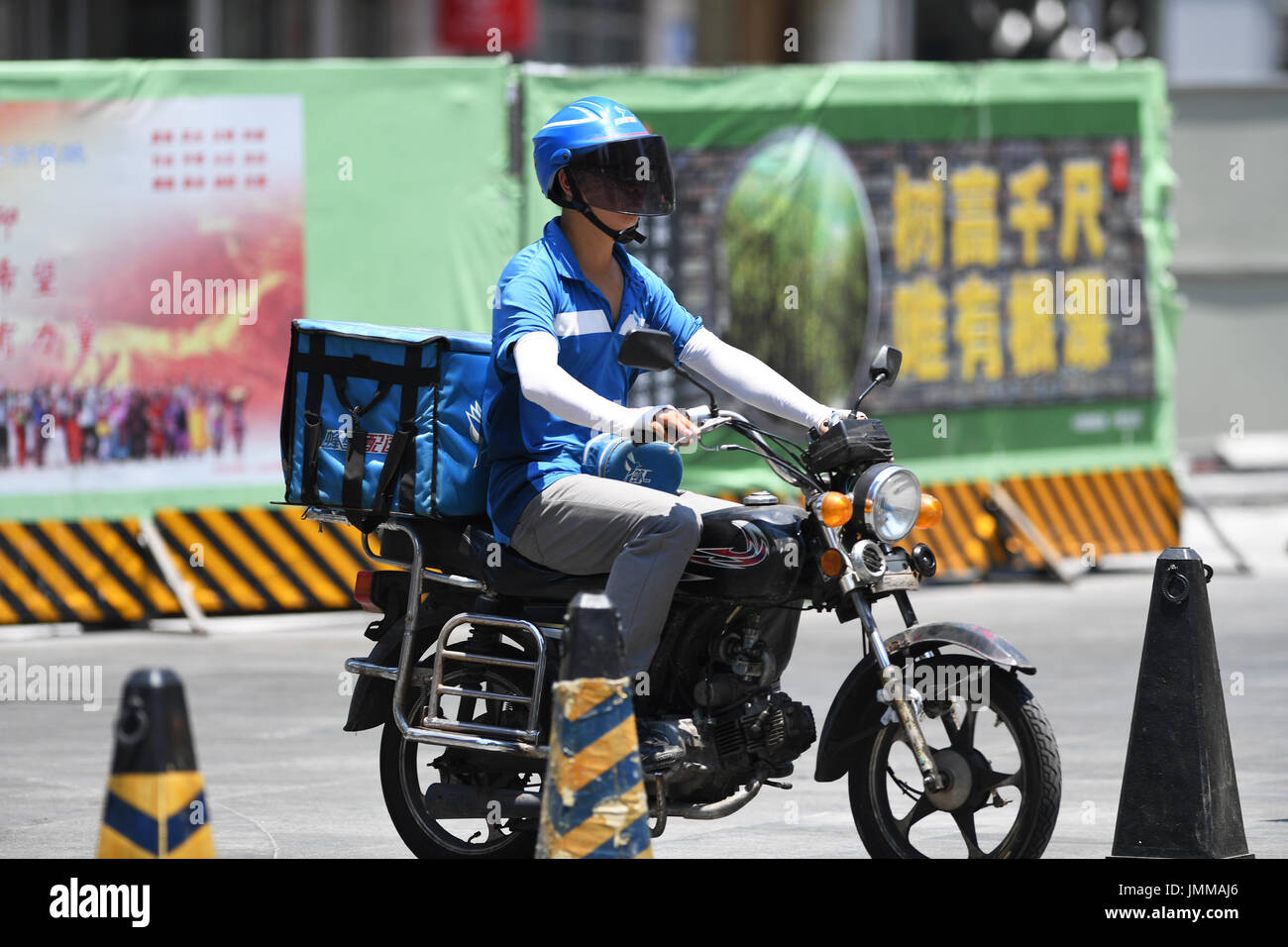 Chongqing, China. 28th July, 2017. A food delivery driver rides in Jiangbei District in Chongqing, southwest China, July 28, 2017. A red alert for high temperatures was issued by Chongqing meteorological observatory on Friday, as some areas saw temperatures surpass 40 degrees Celsius. Credit: Wang Quanchao/Xinhua/Alamy Live News Stock Photo