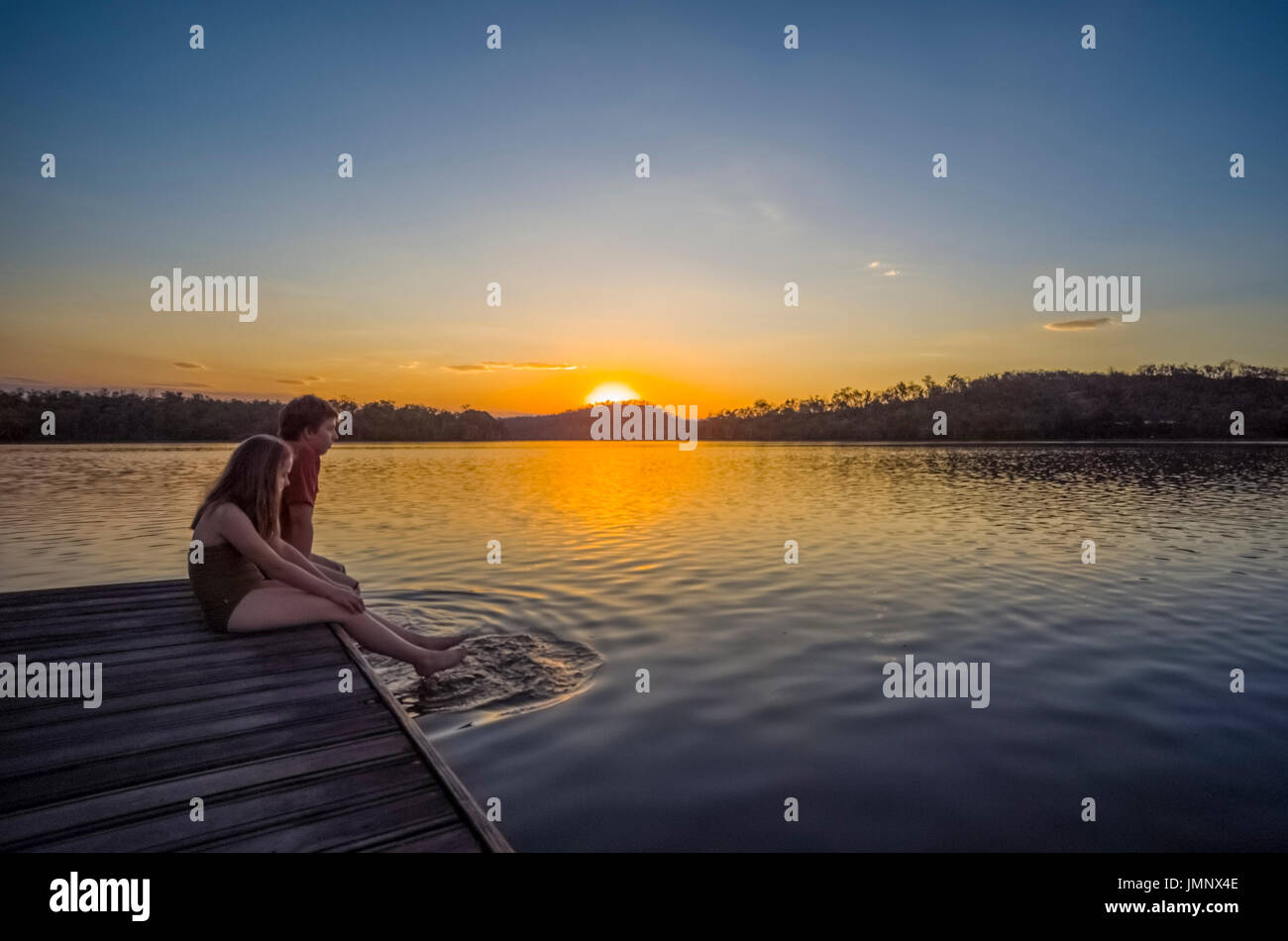 children having fun and jumping into  lake bennett from a jetty at the end of the day Stock Photo