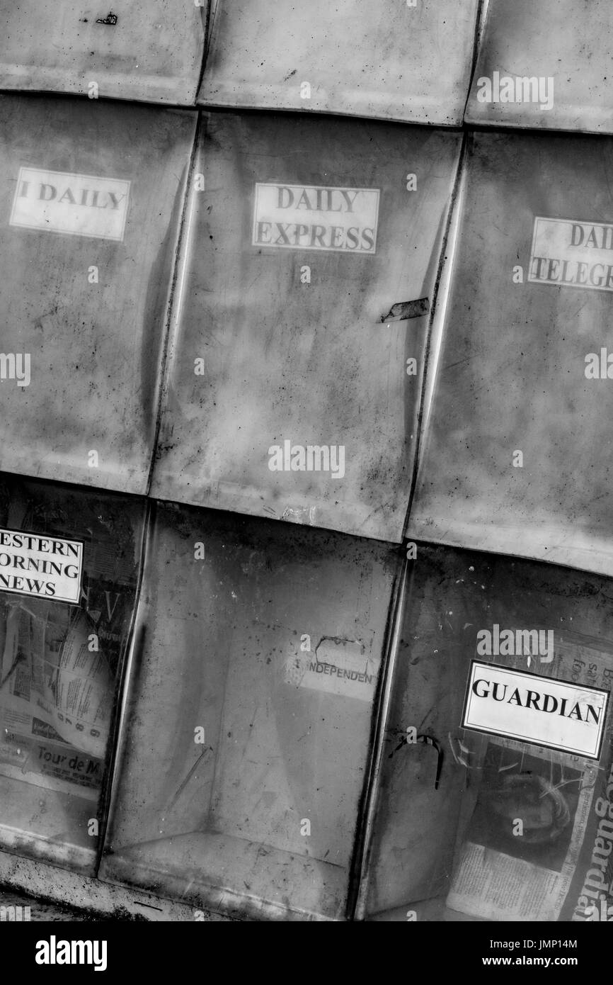 Black and white image of a rather tatty newspaper stand - featuring names of some well known titles but reflecting downfall of traditional newsprint. Stock Photo