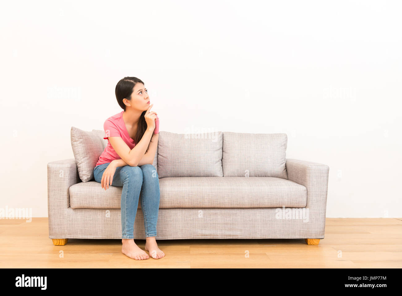 woman sitting on the couch looking and thinking pose on wooden floor