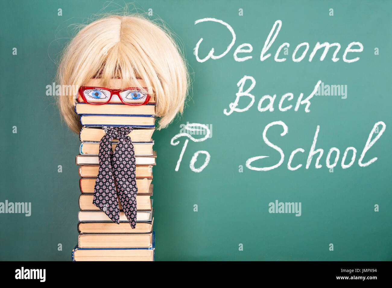 Woman teacher in front of blackboard with title WELCOME BACK TO SCHOOL Stock Photo
