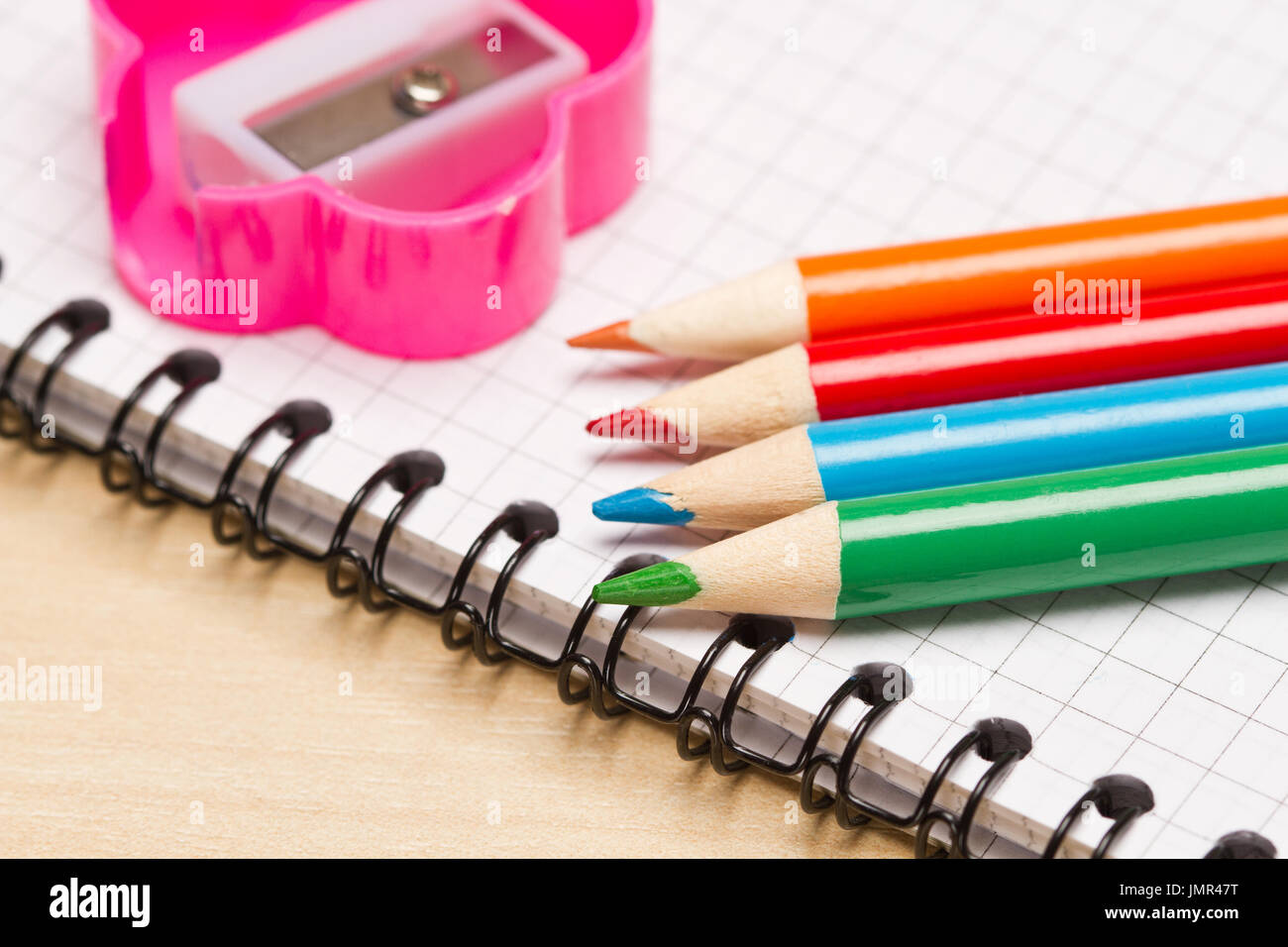 Colored pencils,notebook and pencils sharpener on table Stock Photo