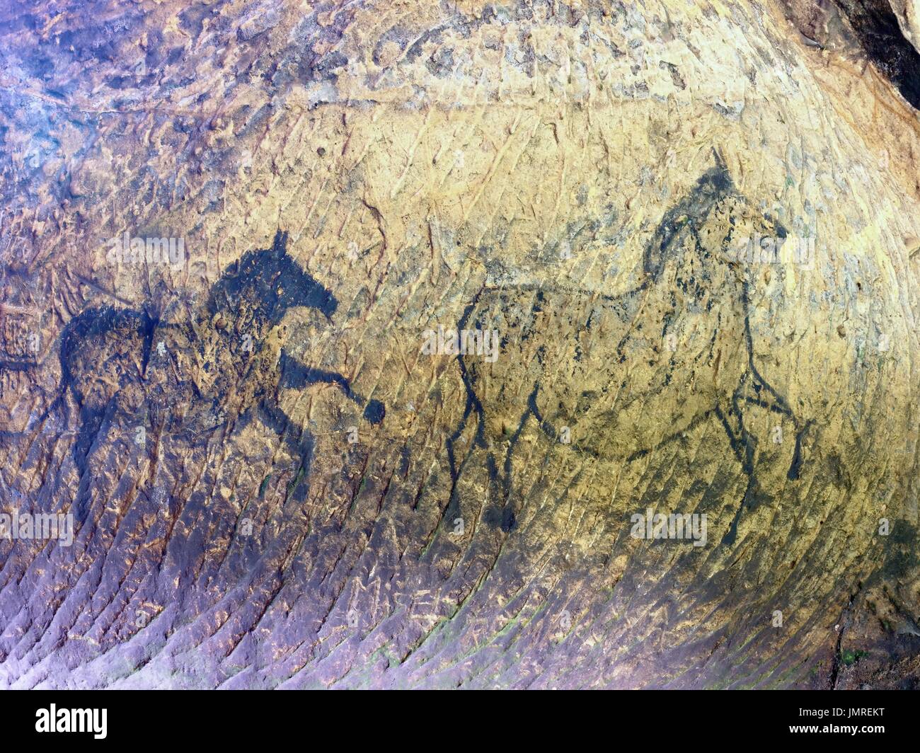 Abstract children art in sandstone cave. Black carbon paint of horses
