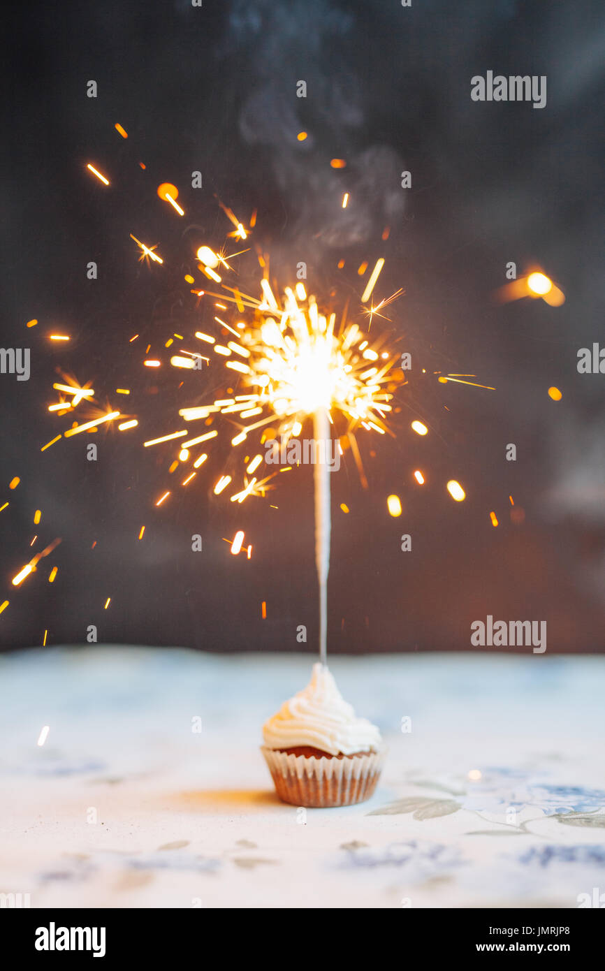 Woman holding tasty cupcake with sparkler, close up Stock Photo