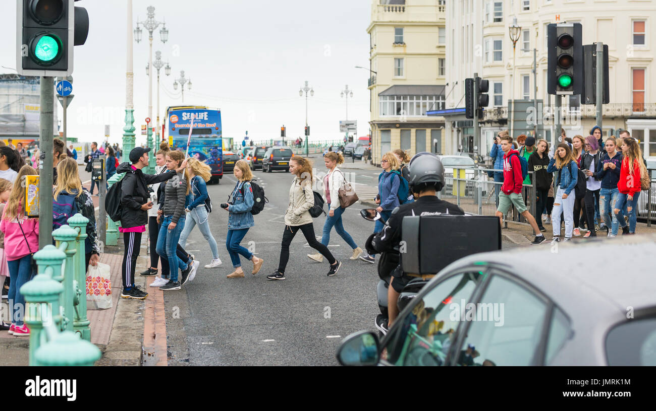 People crossing road at a Pelican crossing after traffic lights for cars have turned green. Stock Photo