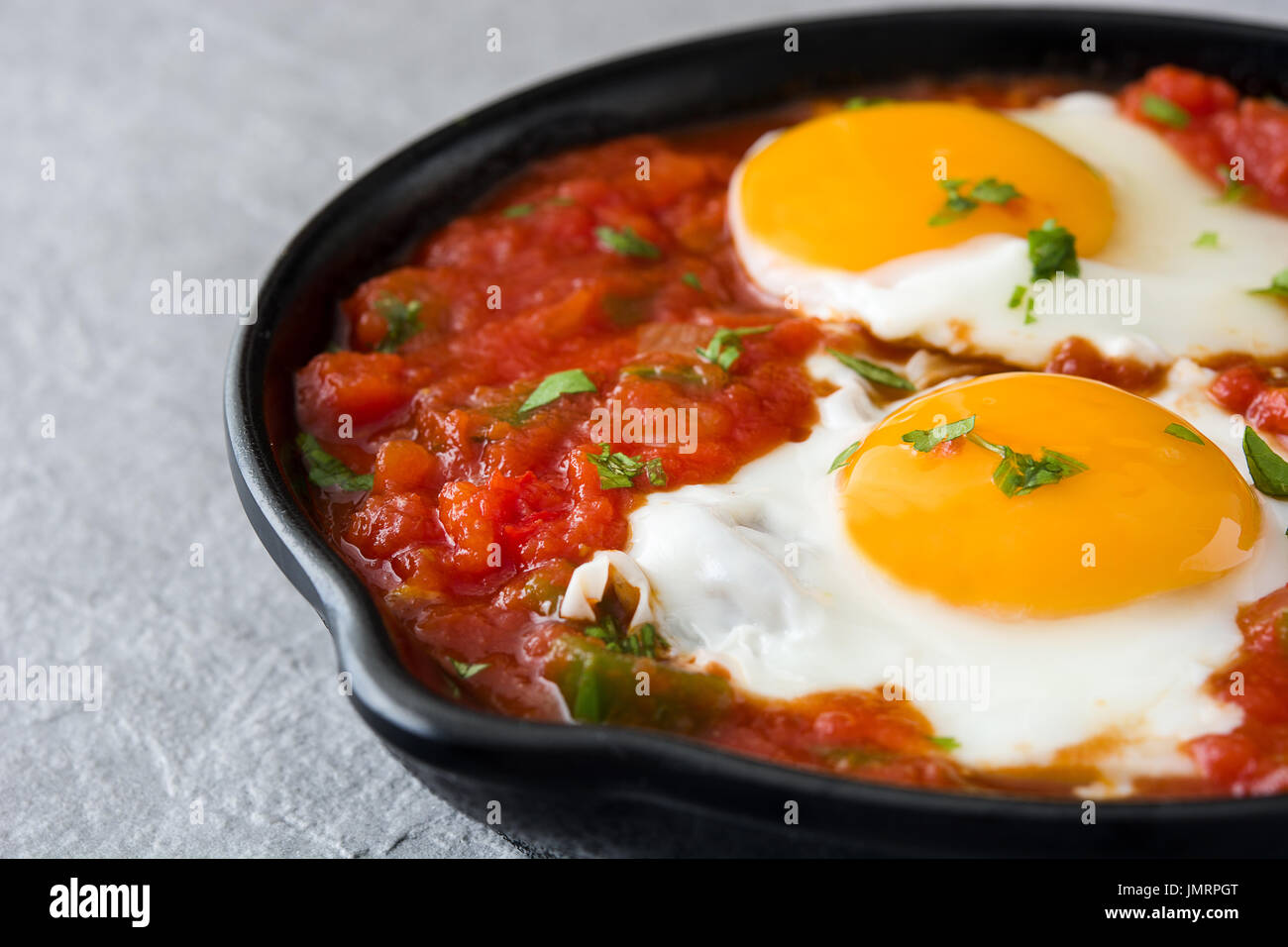 Mexican breakfast: Huevos rancheros in iron frying pan on gray stone Stock Photo