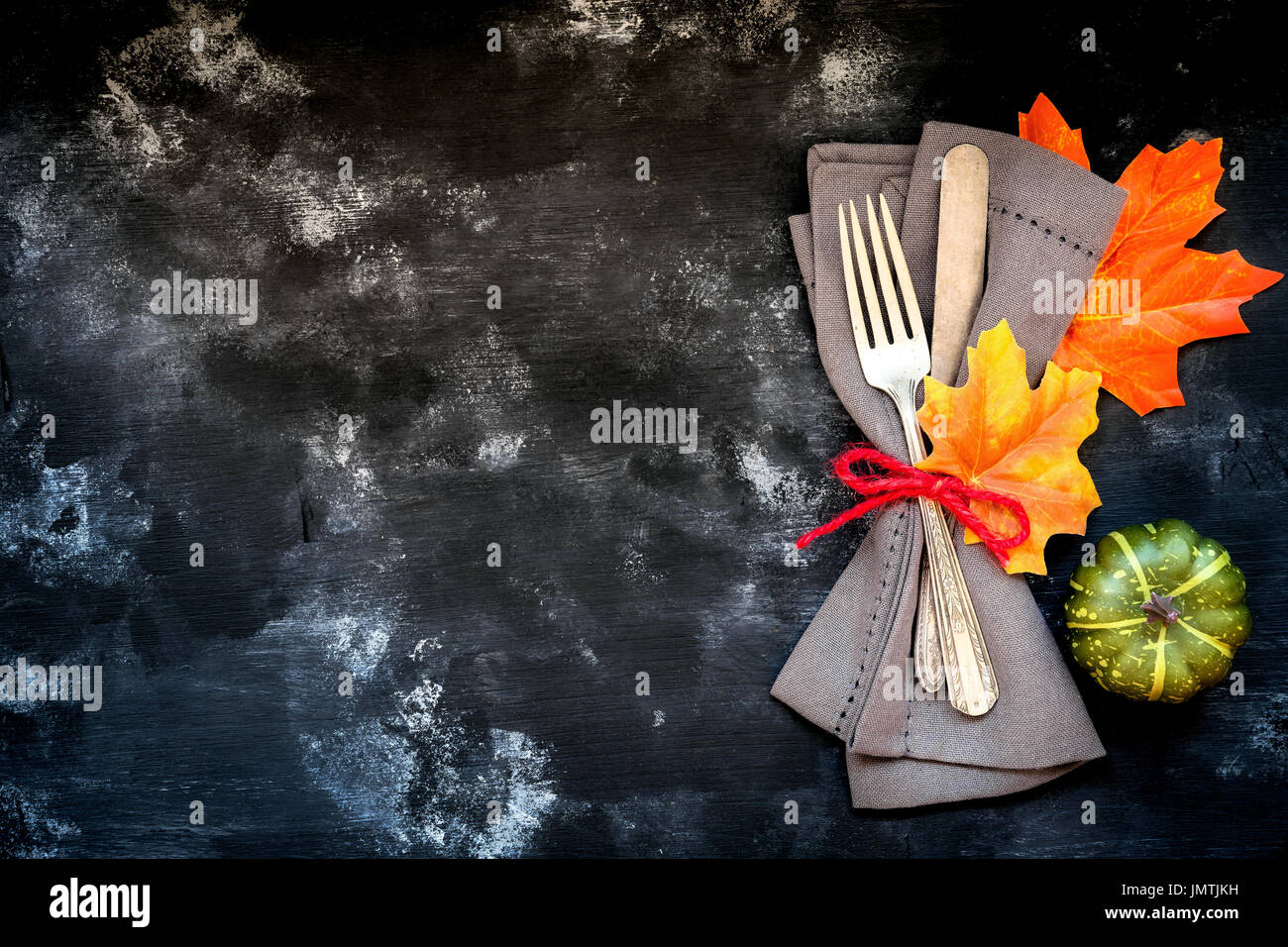 Autumn menu concept - rustic table place setting with a fork and a knife wrapped in a napkin with fall season decorative leaves and pumpkins with copy Stock Photo