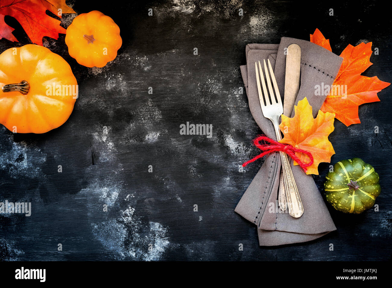 Autumn menu concept - rustic table place setting with a fork and a knife wrapped in a napkin with fall season decorative leaves and pumpkins with copy Stock Photo