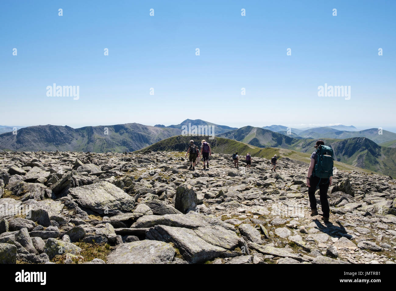 Hikers hiking on rocky Carnedd Dafydd mountain top to Pen Yr Ole Wen in Carneddau mountains of Snowdonia National Park. Ogwen, Conwy, North Wales, UK Stock Photo